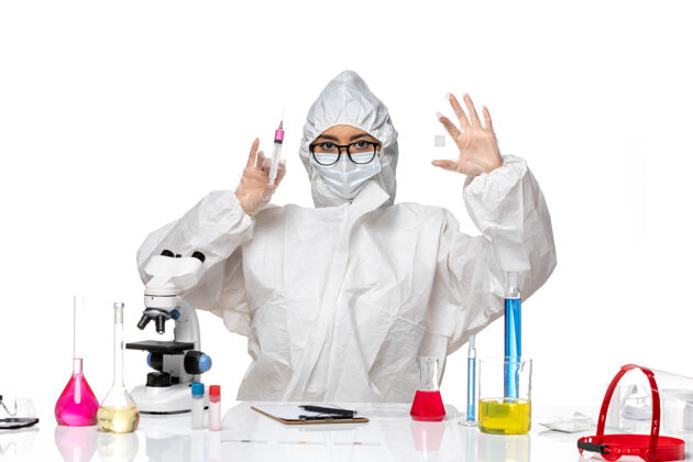 注射前视图身着特殊防护服的女化学家在浅白色背景的covid化学病毒实验室中处理溶液和注射液专业外套医学