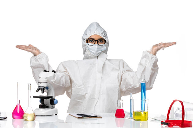 西装前视图穿着特殊防护服的女化学家坐在浅白背景上 解决了化学冠状病毒大流行前面防护坐着