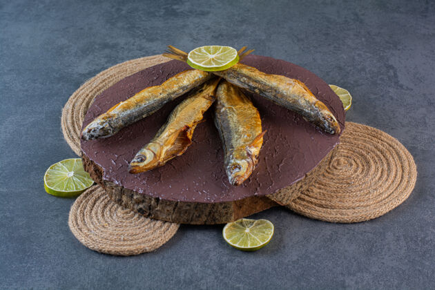 海鲜把柠檬片和干咸鱼放在三脚架的木板上 放在大理石表面烹饪干鱼烘焙