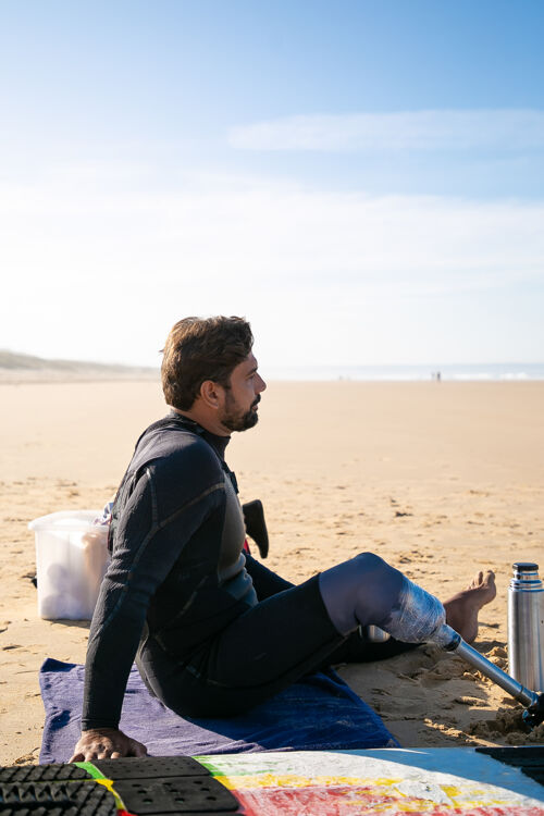 冲浪板中年冲浪者带着假腿坐在沙滩上看海残疾海洋腿