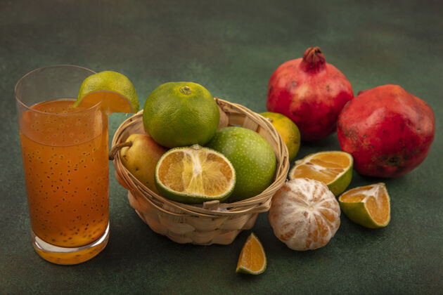 青健康水果的俯视图 如苹果梨猕猴桃放在桶上 新鲜果汁放在玻璃杯上 橘子和石榴被隔离石榴观桶