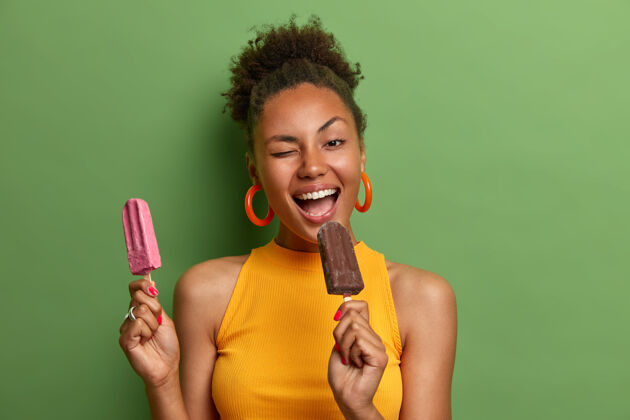 欢呼快乐的卷发女人咬美味的冰淇淋眨眼有意思快乐的表情卷发微笑冷