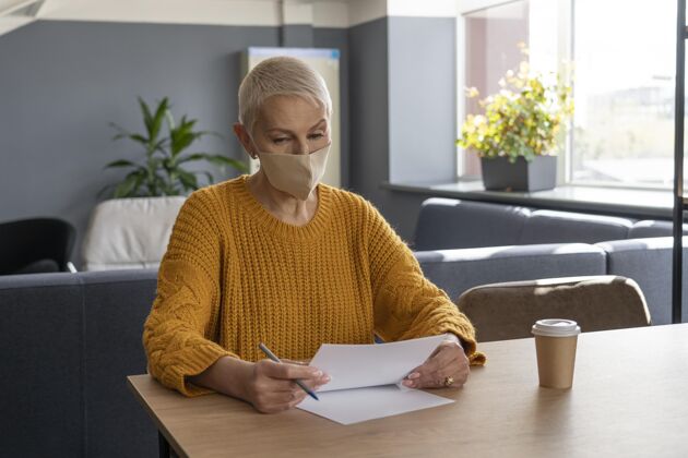 社交距离戴着医用面罩的女人在工作人商业办公室