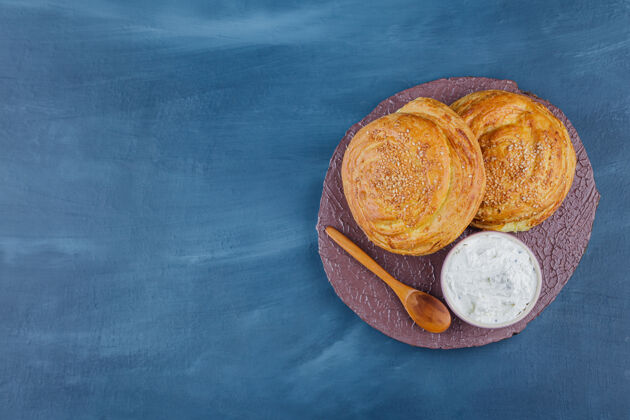 面包皮两个美味的传统糕点和酸奶油在木片上早餐面包勺子