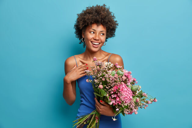 愉快迷人浪漫美丽的非洲裔美国妇女手持大花束接受鲜花花高兴连衣裙