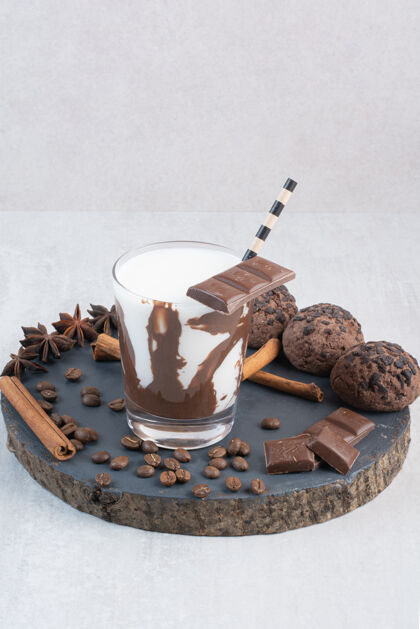 稻草一杯牛奶加稻草 巧克力和饼干放在木片上美味糖果饼干