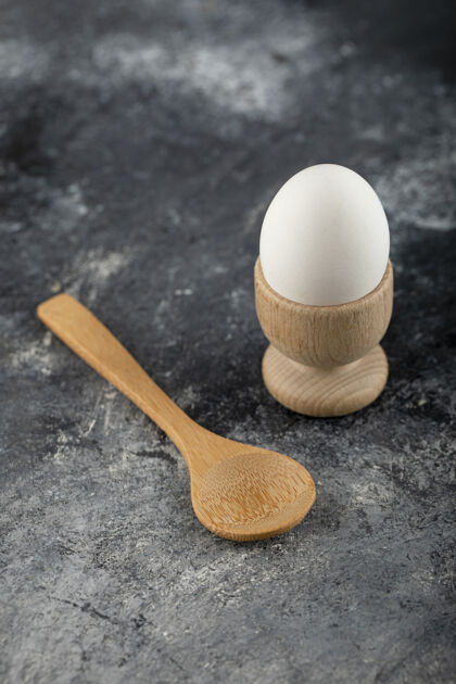 母鸡一个鸡蛋和木制勺子放在大理石表面农场生的农业