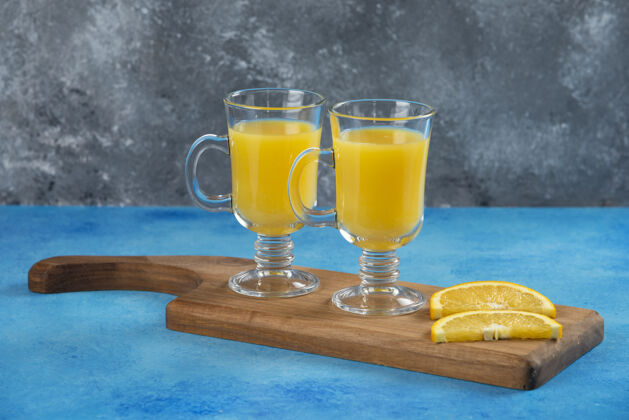 美味在木板上放两杯橙汁新鲜水玻璃杯