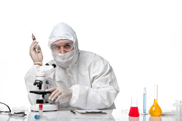 健康正面图：男医生穿着防护服 戴着面罩 在空白处用显微镜观察大流行显微镜男医生