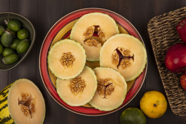 木头新鲜的哈密瓜片放在盘子里的顶视图 碗里放着苹果 柳条托盘上放着苹果 背景是木制的柳条盘子健康