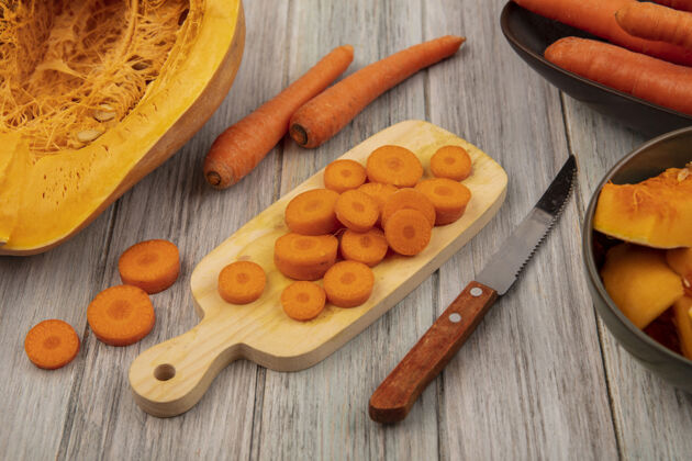 灰色顶视图松脆切碎的胡萝卜在一个木制的菜板上 刀子和胡萝卜放在一个碗上 南瓜被隔离在灰色的木制背景上视图胡萝卜新鲜
