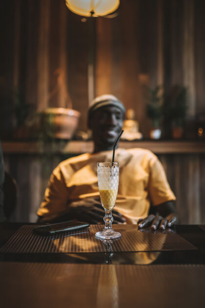 年轻一杯冰沙在一个非洲裔美国男性面前的桌子上的垂直镜头果汁咖啡馆美国