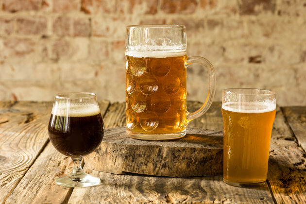 透明木桌上摆着不同种类的深色和浅色啤酒为大朋友聚会准备的美味冷饮概念饮料 乐趣 会议 啤酒节食物酒吧马克杯