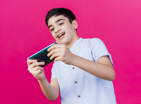 公民兴奋的小男孩在粉红色的墙上玩电话游戏兴奋年轻游戏