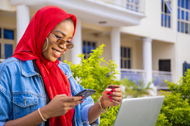 非洲非洲女性拿着信用卡 用笔记本电脑和智能手机开心地在网上购物在线女性信用