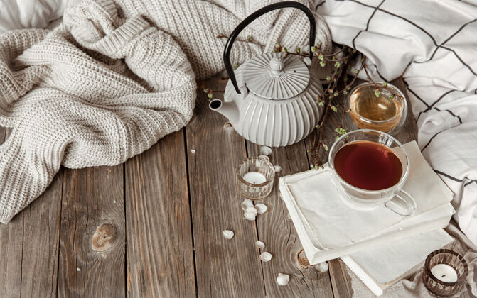 茶温馨的春天静物与蜡烛 茶 水壶在木制表面在一个乡村风格的复制空间毯子杯子床