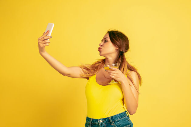 时尚自拍 视频博客 微笑黄色工作室背景上的白人女性肖像美丽的女性模特人类情感的概念 面部表情 销售 广告夏季 旅游 度假夏季人肖像