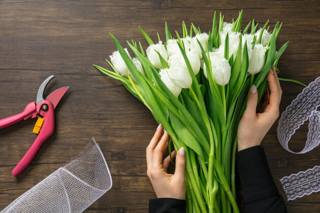开花工作中的花匠：在木制表面上制作不同花朵的时尚现代花束的女人白天广告自然