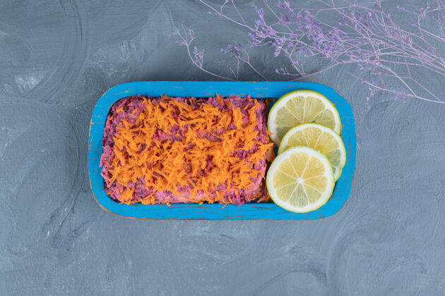 营养胡桃和甜菜沙拉 上面有胡萝卜和柠檬片装饰在大理石背景上美味可口减肥