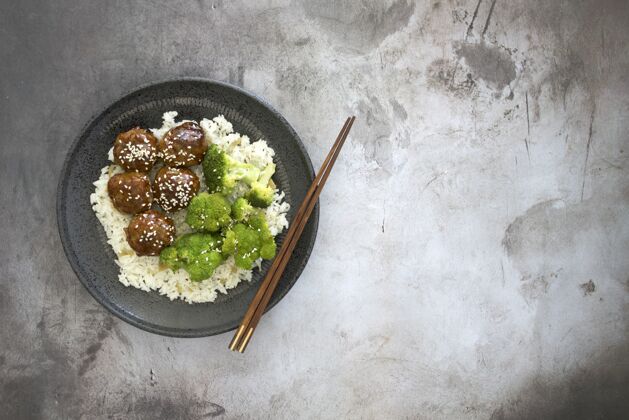 角度用筷子在桌子上的盘子里放着肉丸和花椰菜 可以从高角度观看米饭食物高肉