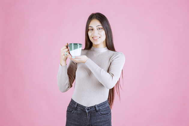 装备女孩拿着一个白绿色的咖啡杯 感觉很积极女人热茶
