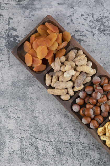 榛子在大理石表面放满各种坚果 饼干和杏干的木板水果什锦零食