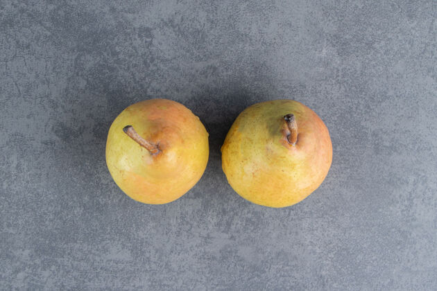 水果两个成熟的红黄色的梨果实被隔离在一个灰色的表面上新鲜美味梨