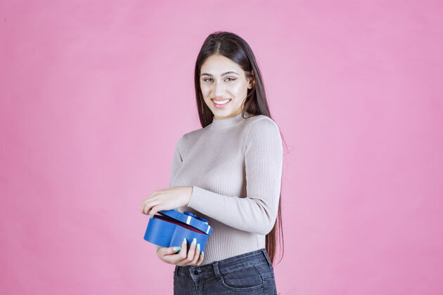 庆祝女孩拿着一个蓝色的礼盒 微笑着人服装周年纪念