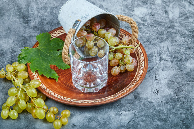 陶瓷小桶内的葡萄陶瓷板和玻璃大理石背景高品质的照片玻璃杯大理石盘子