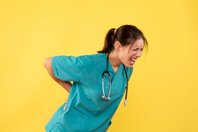 痛苦正面图黄色背景上穿着医用衬衫的女医生背部疼痛衬衫背部设备