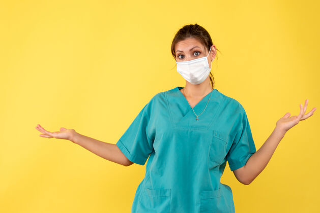 黄色正面图黄色背景上穿着医用衬衫和无菌口罩的女医生视图绝育衬衫