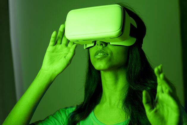 虚拟现实耳机绿色灯光下的女人使用虚拟现实耳机女人增强现实房子