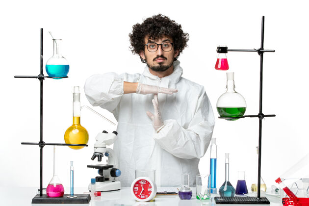 容器正面图身穿白色特别套装的年轻男性科学家在白墙上展示t标志科学covid实验室大流行化学套装特殊视图