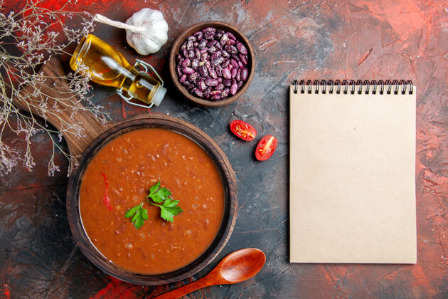 混合上图：棕色砧板上的番茄汤和彩色桌子上的笔记本汤番茄汤碗