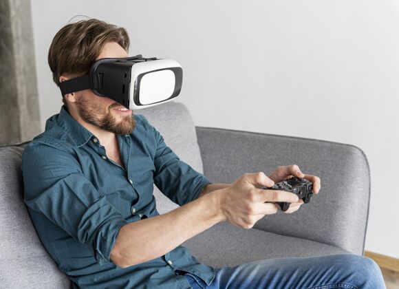 房子坐在沙发上玩虚拟现实耳机玩电子游戏的男人娱乐家庭虚拟现实
