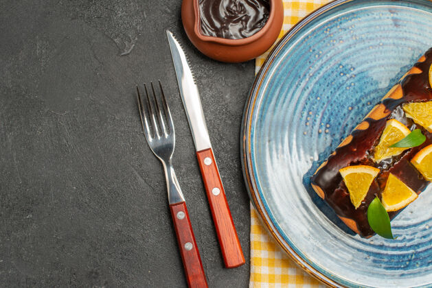 器具用橙子和巧克力装饰的美味蛋糕 用叉子和刀子端上来厨房用具工具设置
