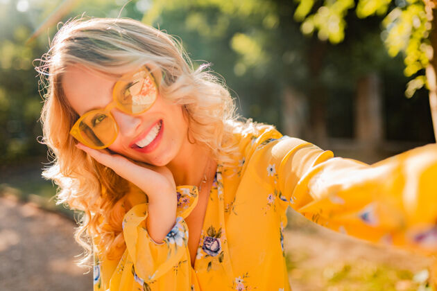 年轻美丽的金发时尚微笑的黄色女衬衫戴墨镜自拍照片的肖像肖像女人眼镜