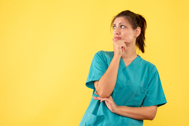 人前视图穿着医疗衬衫的女医生在黄色背景上思考病毒思考肖像