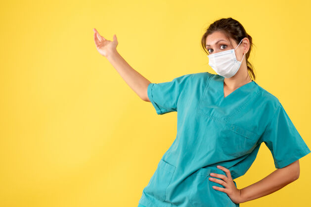 人正面图黄色背景上穿着医用衬衫和无菌口罩的女医生正面衬衫表情