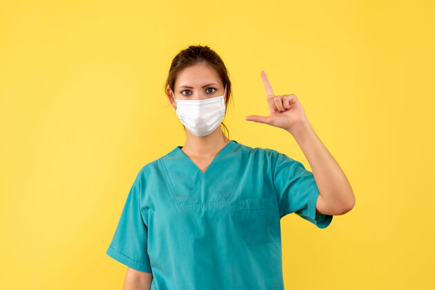 健康正面图黄色背景上穿着无菌口罩医用衬衫的女医生成人女医生病毒