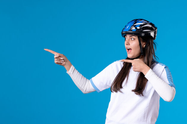 成人正面图蓝色墙上穿着运动服戴着头盔的年轻女性头盔微笑自行车