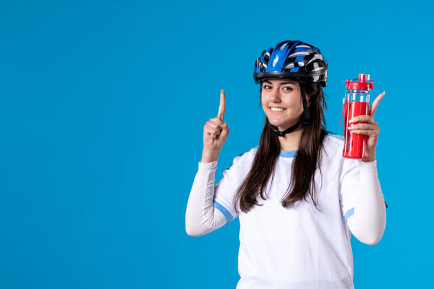 视图正面图蓝色墙上穿着运动服戴着头盔的年轻女性头盔微笑肖像