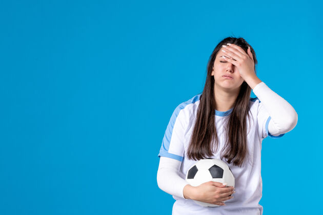 体育前视图：蓝色墙上有足球的年轻女性人肖像正面