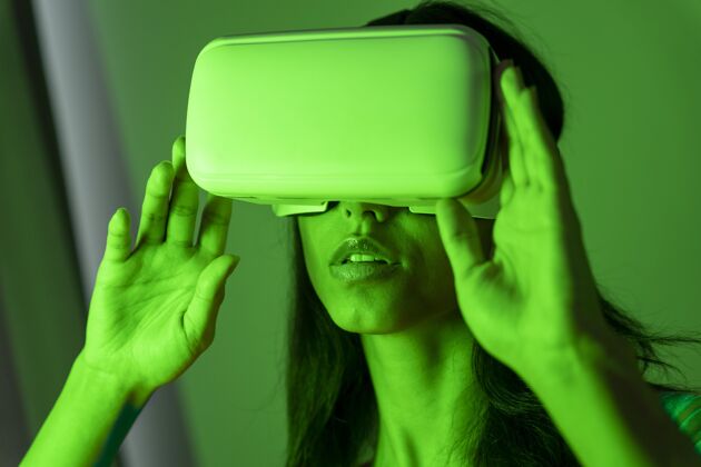 娱乐绿色灯光下的女人使用虚拟现实耳机水平乐趣增强现实
