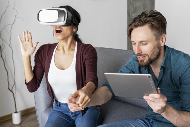 虚拟现实耳机男人和女人在家里使用虚拟现实耳机和平板电脑享受增强现实虚拟现实