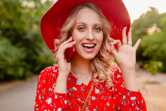年轻迷人的时尚金发微笑的妇女在稻草红色帽子和衬衫夏季时尚服装画像在电话交谈积极的姿态情感金发女士女人