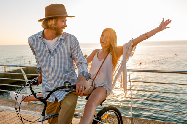 旅行骑自行车旅行的年轻帅哥美女 夏日夕阳海边的浪漫情侣 波西米亚时尚装扮 朋友们在一起玩得开心女性男性乐趣