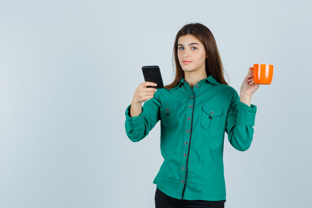 眼睛年轻的女士拿着橘色的茶杯和手机 穿着衬衫 看起来很自信 前视感性女士健康