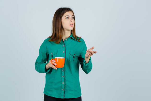 人年轻的女士拿着一杯橘色的茶 穿着衬衫 看起来很专注 前视图放松治疗健康