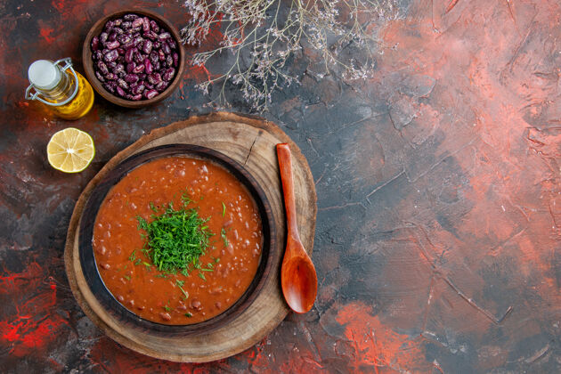 容器上图是一个棕色碗里的经典番茄汤 油瓶豆子和勺子放在五颜六色的桌子上勺子蔬菜番茄汤